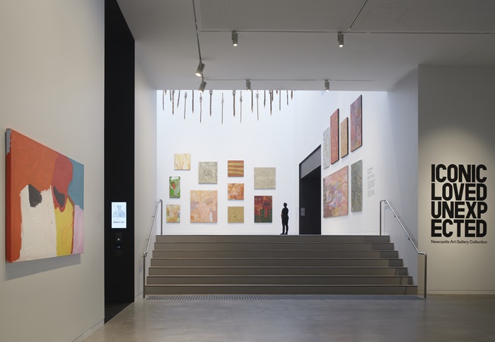 Photo looking across a set of stairs toward installed works from the collection, hung from the walls and the ceiling