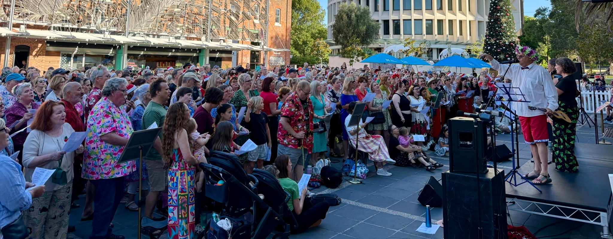 Registrations are now open for Newcastle’s favourite festive community chorus, with Civic Theatre’s One Song Sing event returning to Wheeler Place next month. This will be the third year Novocastrians have been given an hour to learn a special Christmas song before joining together in a one-off public pop-up performance led by community music group The Sum of the Parts. Following two hugely successful renditions of Paul Kelly’s Christmas classic ‘How to Make Gravy’, this year’s mashup will blend the nostalgia of Wham’s holiday hit ‘Last Christmas’ with the modern pop song ‘Birds of a Feather’ by Billie Eilish. Executive Manager Civic Theatre Leonie Wallace said the event is a way of celebrating the Christmas season with the community. “One Song Sing is our way of saying thank you to the community for their support of the theatre during the past year,” Ms Wallace said. “We look forward to welcoming the community back to Wheeler Place on 22 December for another wonderful celebration in the heart of the Civic precinct.” Chair of City of Newcastle’s Community and Culture Strategic Advisory Committee Cr Jenny Barrie said the event offers a unique opportunity for people of all ages and abilities to share in the fun of a festive community sing-along.  "One Song Sing has attracted around 3,000 combined registrations during the past two years and has become a festive favourite, uniting locals in a relaxed, joyful singing experience that connects and celebrates community spirit,” Cr Barrie said. The free sing-along will start from 5.30pm on Monday 22 December. Visit the Civic Theatre website to register for the event.   No prior singing experience is required as the event is inclusive, welcoming and designed to make everyone feel part of something special.  The performance will also be recorded and shared online, allowing the wider community and those who are unable to make it on the day to experience the festive spirit. A link to last year’s performance can be found here